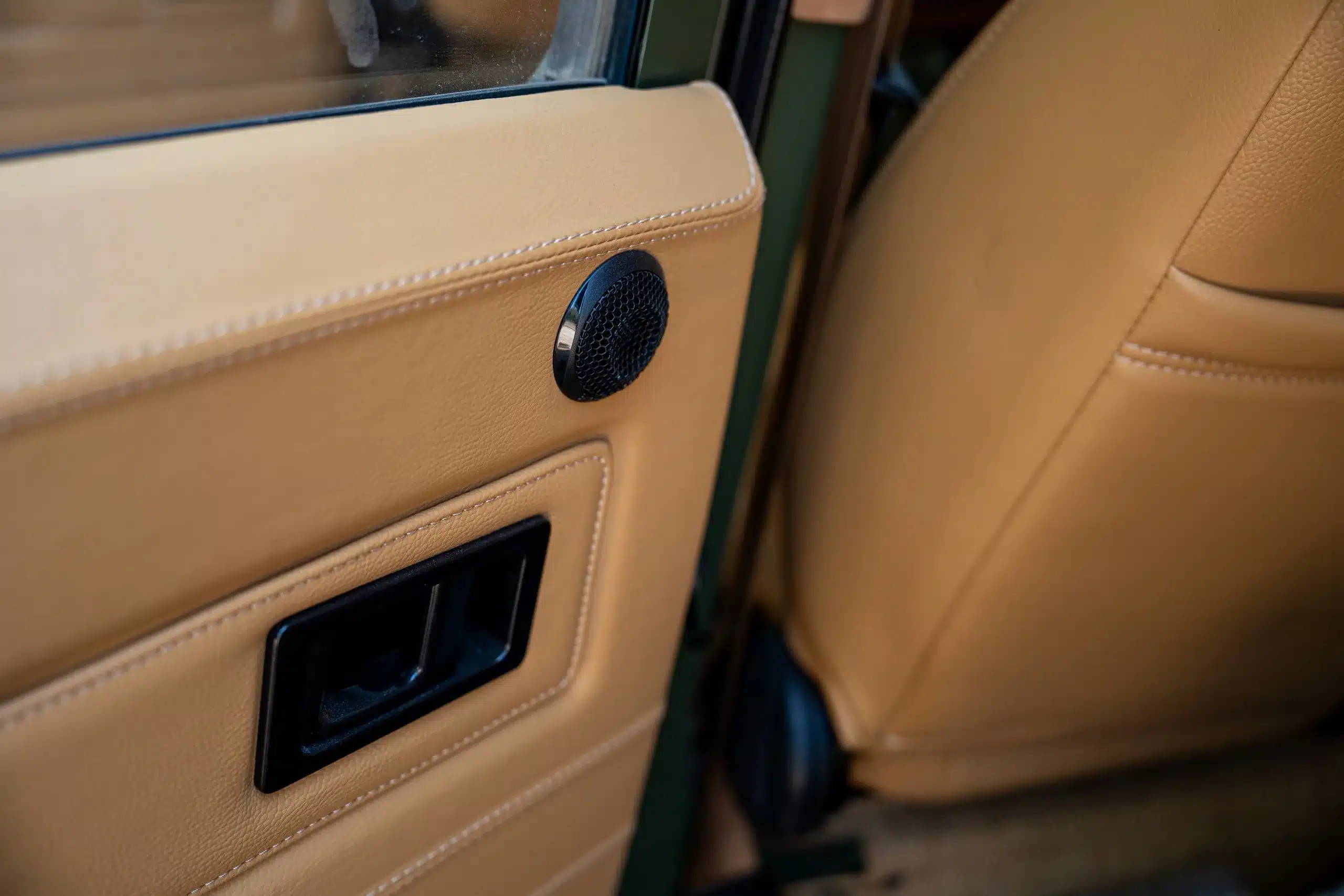 Beigefarbene Leder-Türverkleidung mit rundem Lautsprecher und schwarzem Türgriff eines Land Rover Defender 110 (1999)