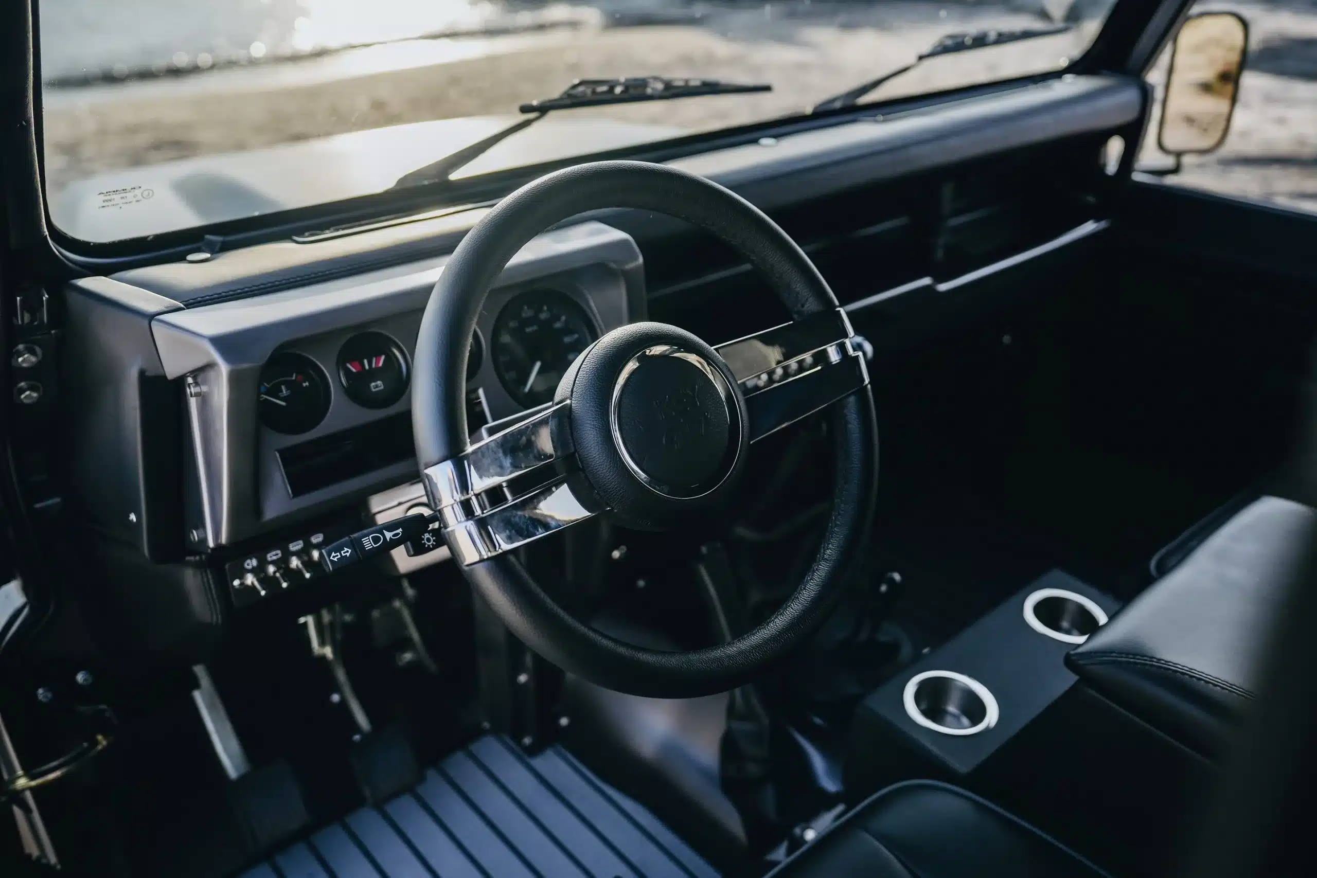 Blick auf das Cockpit eines Land Rover Defender 110 von 1999 mit Lenkrad, Armaturenbrett und Mittelkonsole.