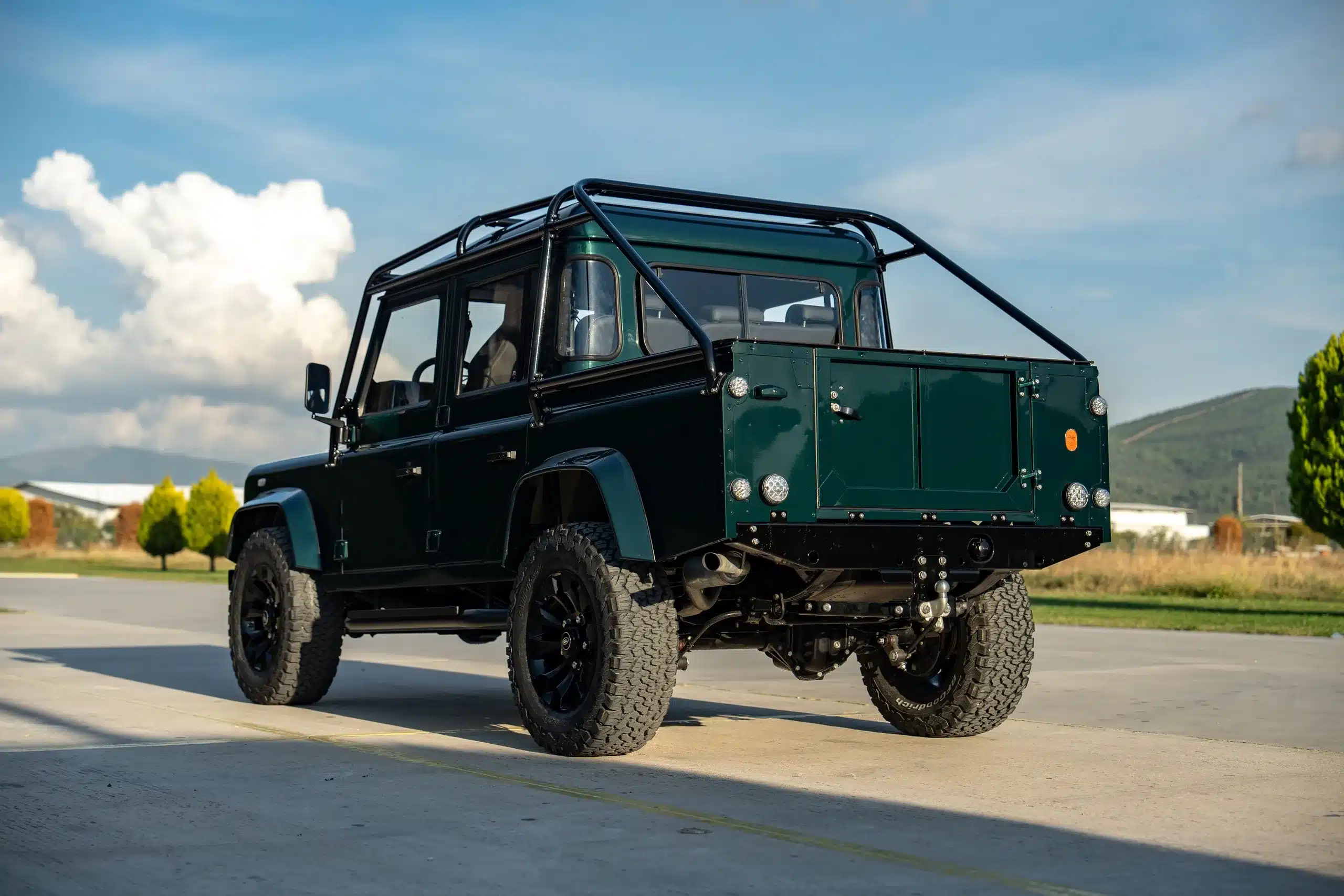 Land Rover Defender 110 in Viridian Green, Heckansicht, auf offenem Gelände, Baujahr 1994.