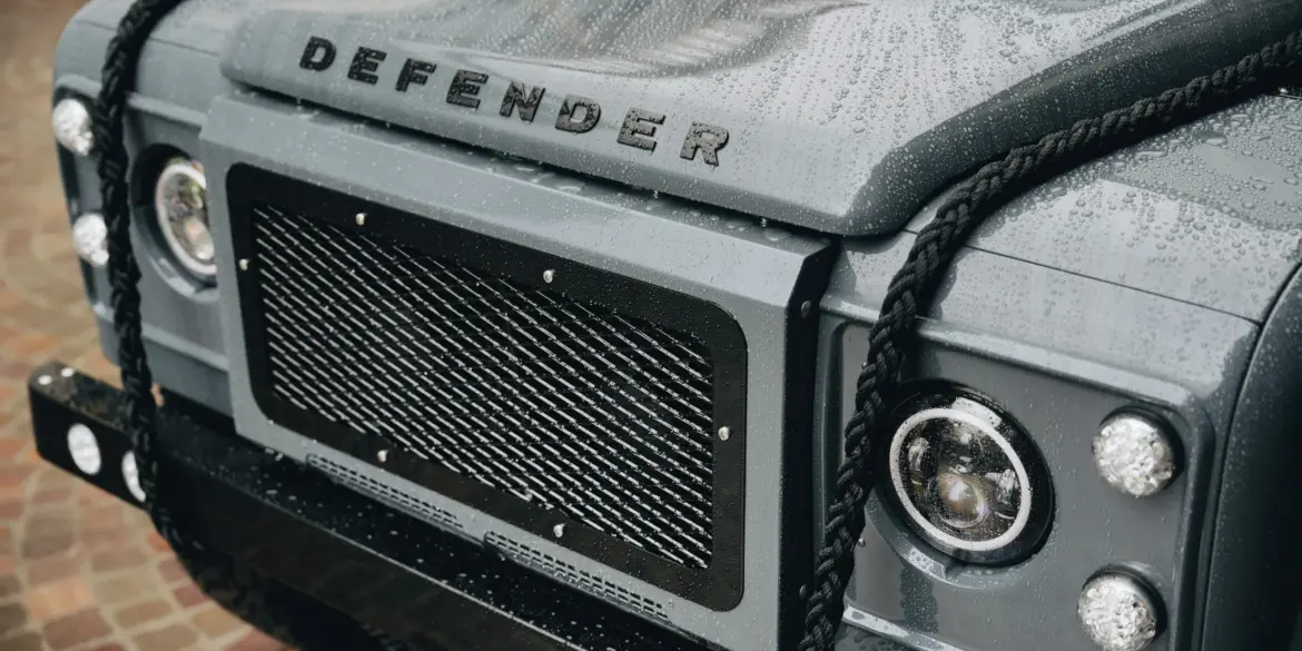 Detailaufnahme der Front eines Land Rover Defender 110 mit Regenperlen auf der Motorhaube