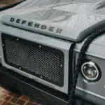 Detailaufnahme der Front eines Land Rover Defender 110 mit Regenperlen auf der Motorhaube