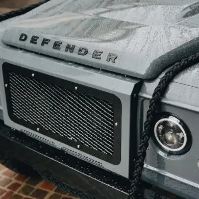 Detailaufnahme der Front eines Land Rover Defender 110 mit Regenperlen auf der Motorhaube