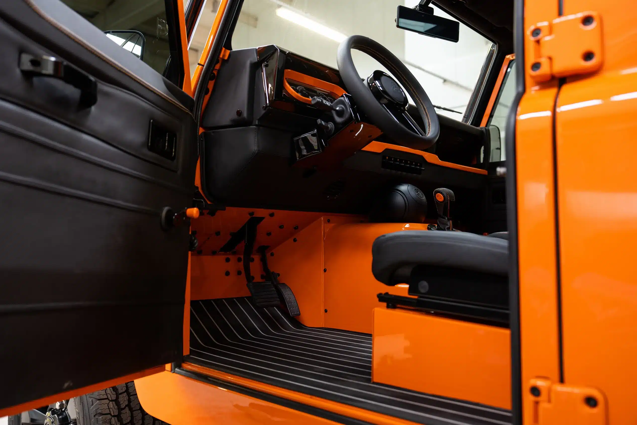 Innenansicht eines orangefarbenen Land Rover Defender 110 von 1991 mit 6-Gang-Handschaltung und schwarzer Ausstattung