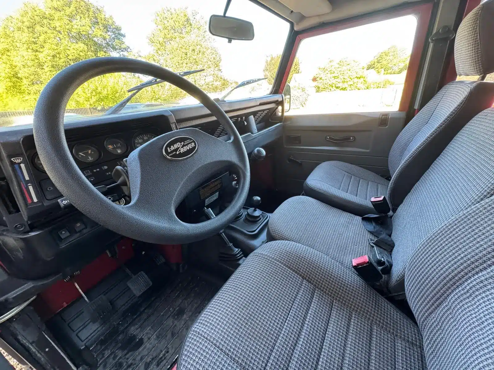 Innenansicht eines Land Rover Defender 130 300Tdi, Blick auf Lenkrad, Schalthebel und Vordersitze.