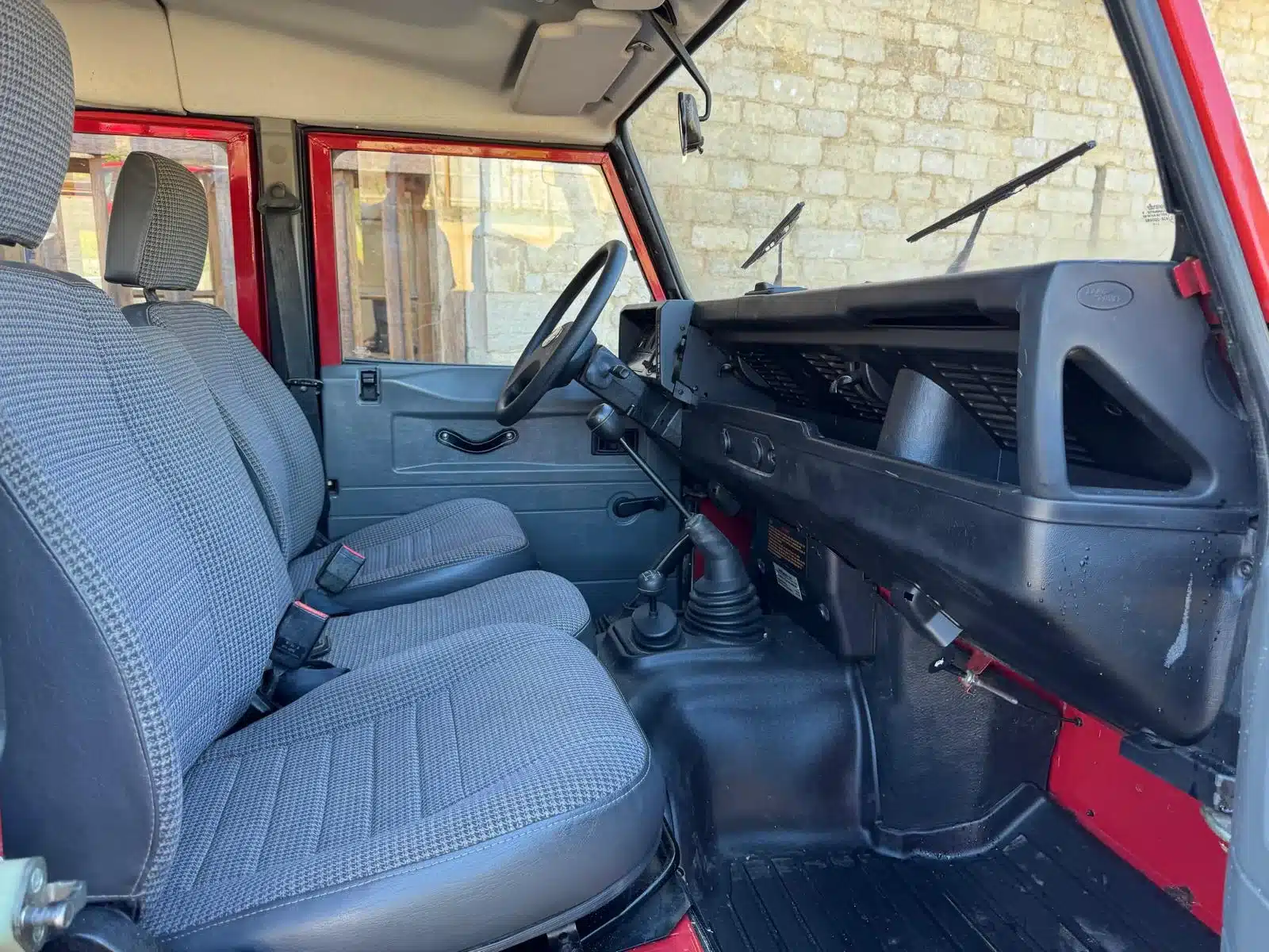 Innenansicht eines Land Rover Defender 130 300Tdi, Vordersitze und Armaturenbrett in gutem Zustand.