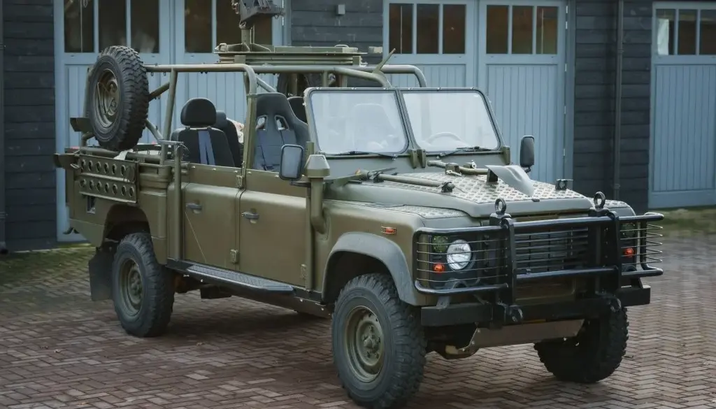 Land Rover Defender 130 WMIK 2013 ohne Türen und Dach in militärischer Ausführung vor Garage