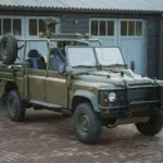Land Rover Defender 130 WMIK 2013 ohne Türen und Dach in militärischer Ausführung vor Garage