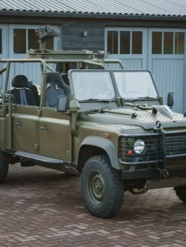 Land Rover Defender 130 WMIK 2013 ohne Türen und Dach in militärischer Ausführung vor Garage