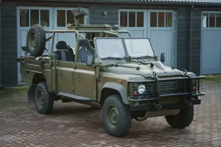 Land Rover Defender 130 WMIK 2013 ohne Türen und Dach in militärischer Ausführung vor Garage