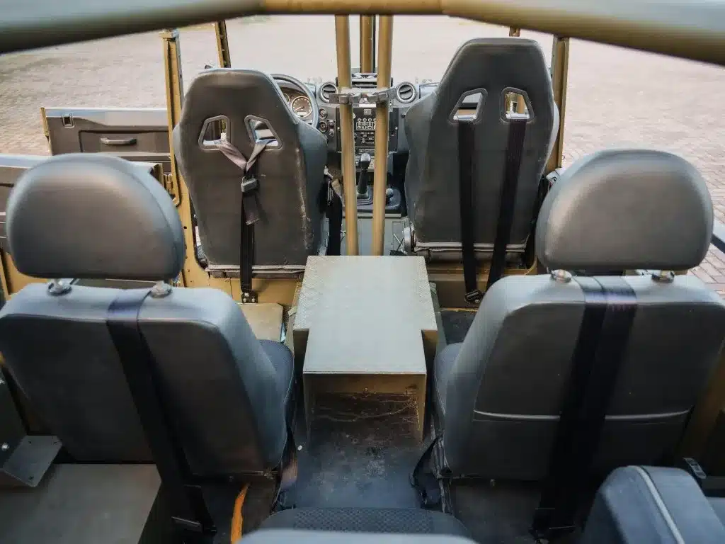 Offener Innenraum eines Land Rover Defender 130 WMIK mit Überrollkäfig und vier Sitzen.