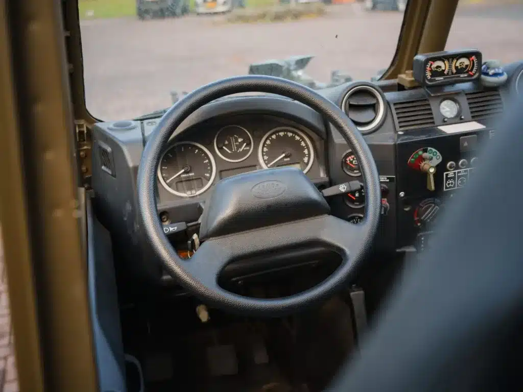 Innenraumansicht des Land Rover Defender 130 WMIK mit Lenkrad und Instrumenten.