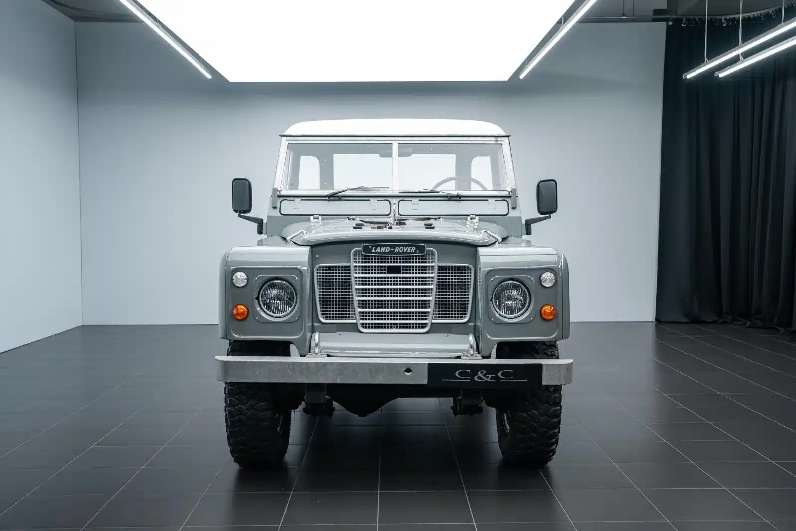 Frontansicht eines restaurierten Land Rover Serie III 109 LWB in militärischer Ausführung, aufgenommen in heller Umgebung.