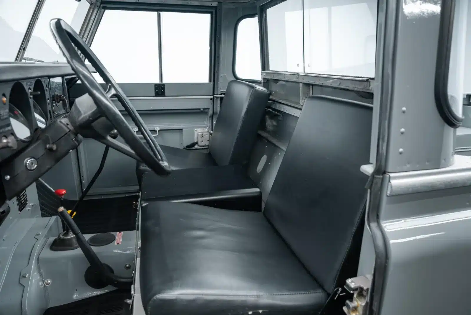 Innenansicht eines Land Rover Serie III 109 LWB mit einfacher Sitzbank und klassischem Armaturenbrett, restaurierter Zustand