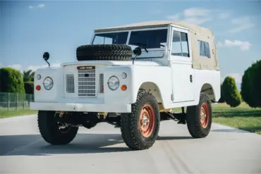 Frontansicht eines Land Rover Series III von 1973 in weiß mit Ersatzrad auf der Motorhaube und beigem Verdeck