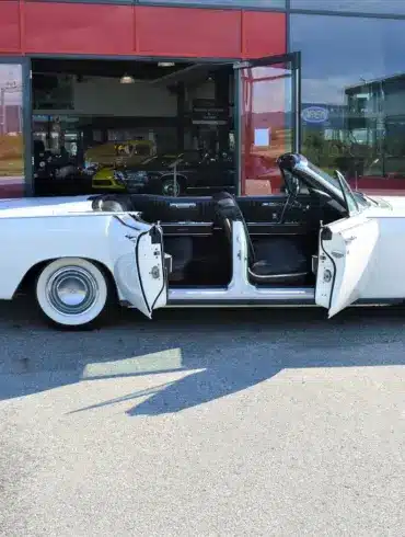 Lincoln Continental 4-Türer Cabriolet von 1967 in Weiß mit geöffneten Türen vor einem Autohaus.