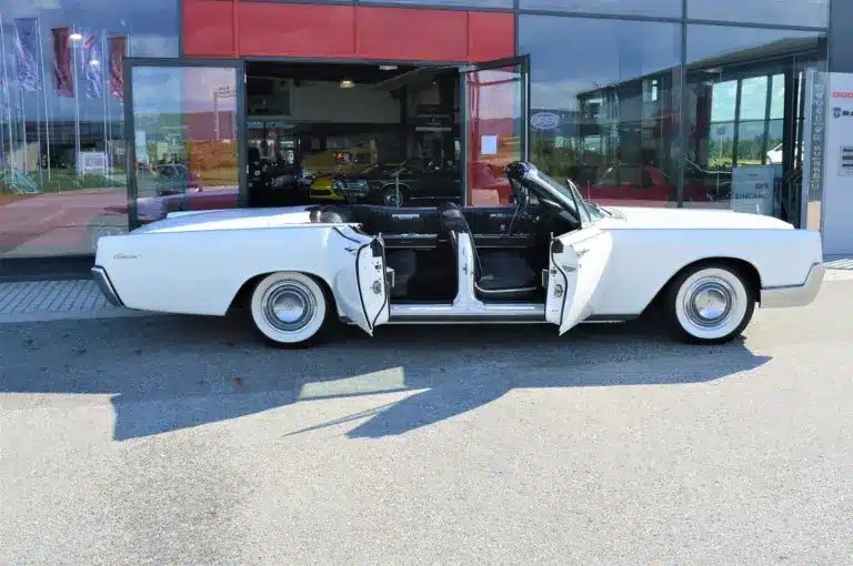 Lincoln Continental 4-Türer Cabriolet von 1967 in Weiß mit geöffneten Türen vor einem Autohaus.