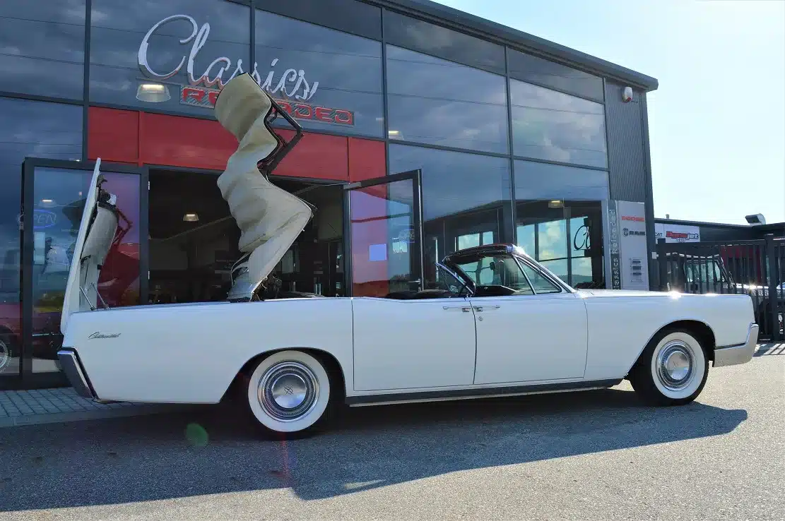 Lincoln Continental 4-door Convertible von 1967 mit weißer Karosserie und geöffnetem Verdeck vor einem Autohaus