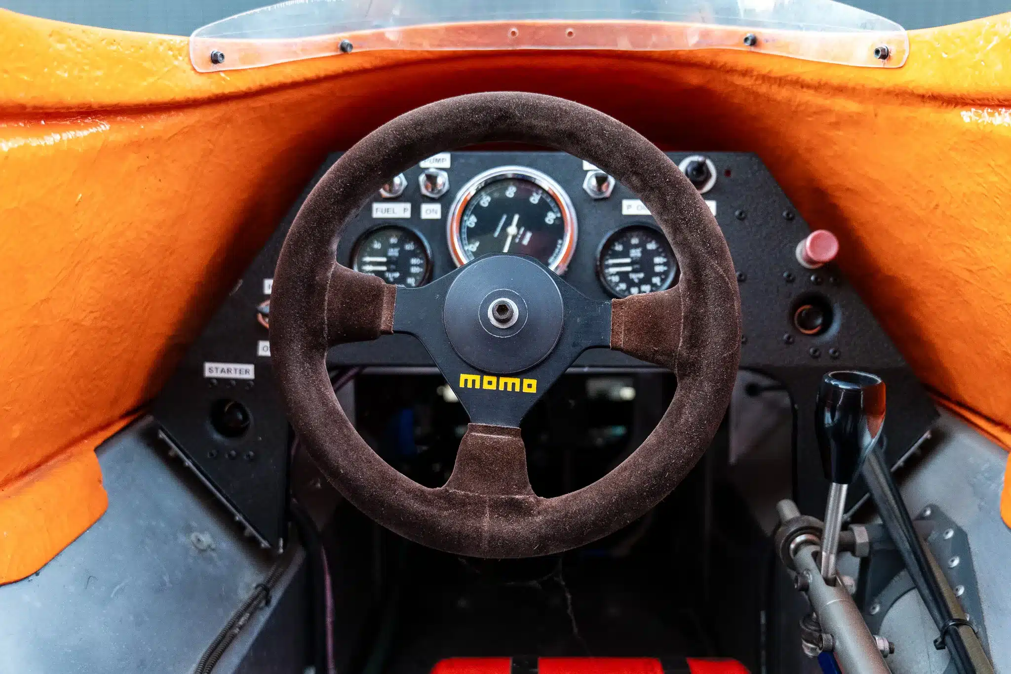 Innenansicht des Cockpits eines March 773 von 1977 mit MOMO-Lenkrad, Schalthebel und klassischen Rundinstrumenten.