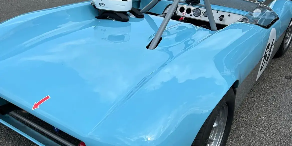 Rennwagen Merlyn Mk4A von 1964 in hellblau, geparkt im Fahrerlager mit aufgesetztem Helm