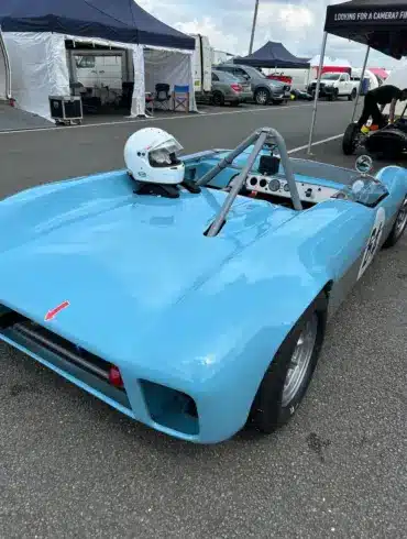 Rennwagen Merlyn Mk4A von 1964 in hellblau, geparkt im Fahrerlager mit aufgesetztem Helm
