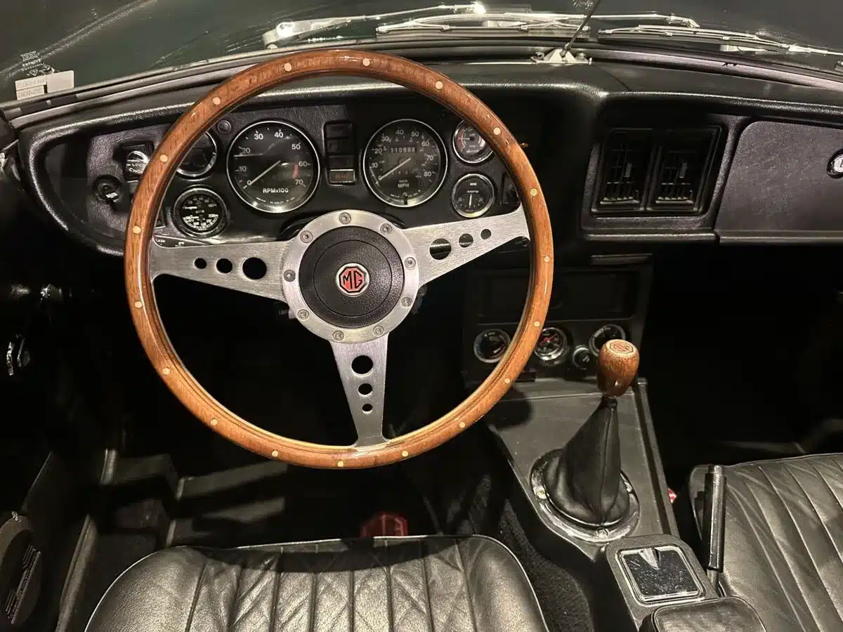 Innenraum eines MGB MkIII Roadster von 1974 mit Moto-Lita-Holzlenkrad, schwarzen Sitzen und Schaltknauf