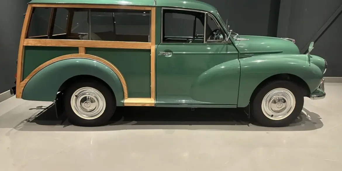 Grüner Morris Minor 1000 Traveller von 1964 mit sichtbarem Holzrahmen, im Ausstellungsraum seitlich fotografiert
