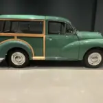 Grüner Morris Minor 1000 Traveller von 1964 mit sichtbarem Holzrahmen, im Ausstellungsraum seitlich fotografiert