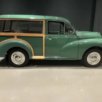 Grüner Morris Minor 1000 Traveller von 1964 mit sichtbarem Holzrahmen, im Ausstellungsraum seitlich fotografiert