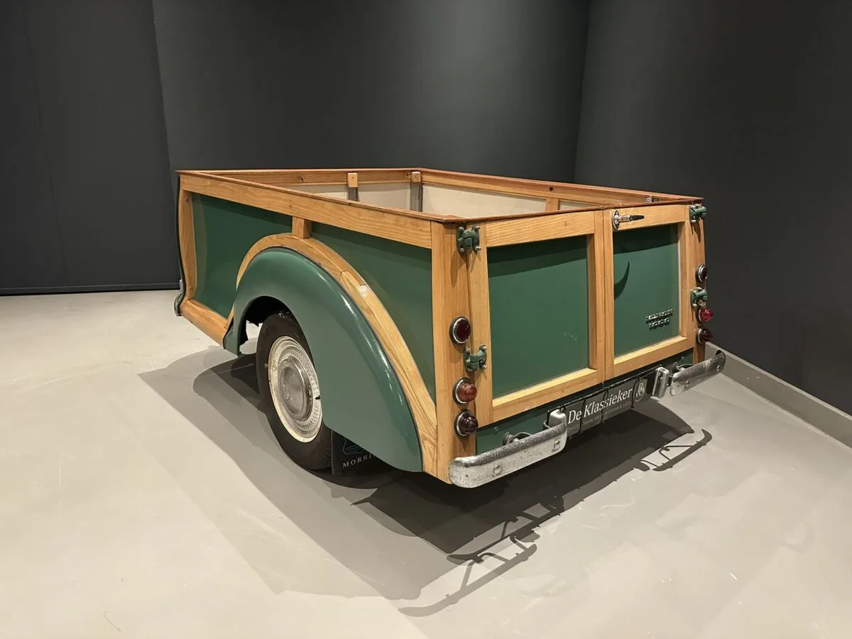 Gepäckanhänger mit Holzrahmen, passend zum Morris Minor 1000 Traveller, auf einem hellen Boden vor dunklem Hintergrund.