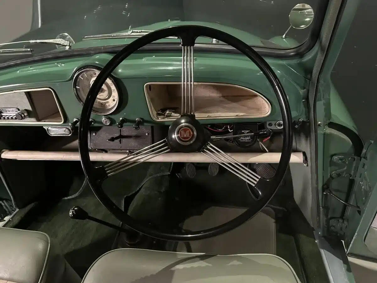 Armaturenbrett und Lenkrad eines Morris Minor 1000 Traveller von 1964 in grünem Interieur, Rechtslenker-Ausführung
