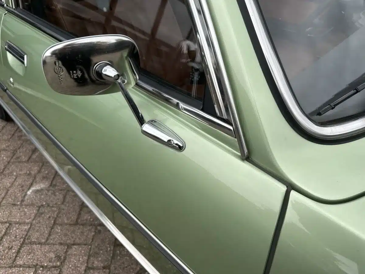 Nahaufnahme eines Außenspiegels und der Tür eines Peugeot 504 Ti in grün