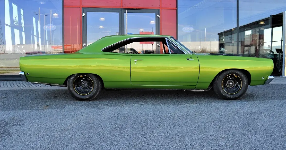 Grüner Plymouth Road Runner 383, Baujahr 1968, vor einem modernen Gebäude