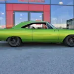 Grüner Plymouth Road Runner 383, Baujahr 1968, vor einem modernen Gebäude