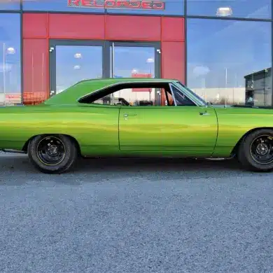 Grüner Plymouth Road Runner 383, Baujahr 1968, vor einem modernen Gebäude