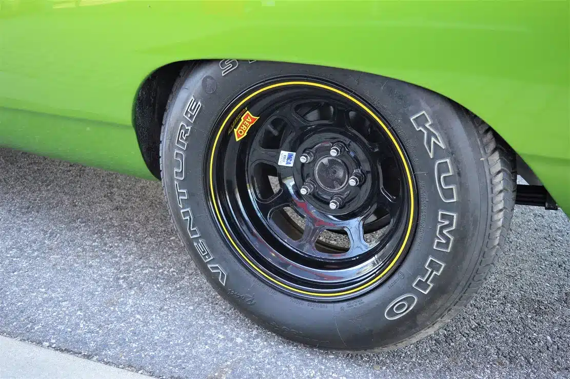 Schwarzes Vorderrad mit gelber Zierlinie und Kumho-Reifen an einem grünen Plymouth Road Runner 383, Modelljahr 1968