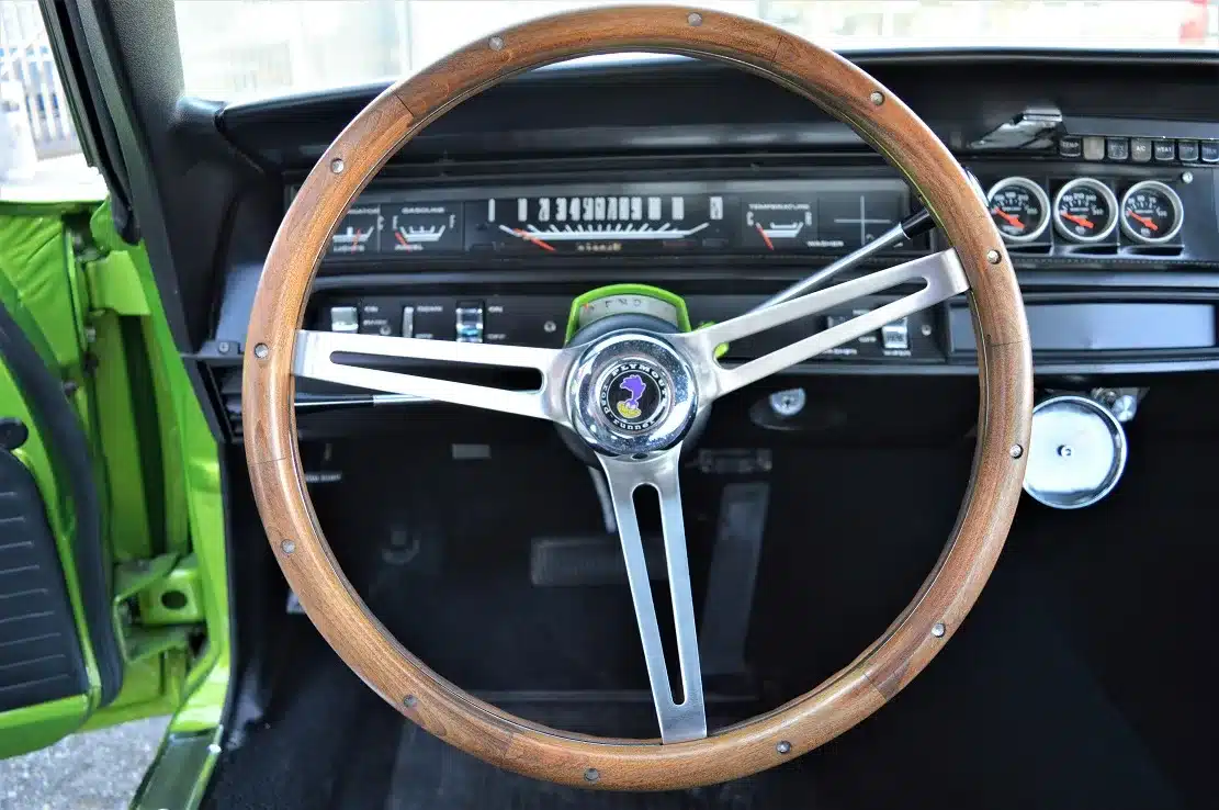 Innenansicht eines Plymouth Road Runner 383 mit Fokus auf das originale Holzlenkrad und die Instrumententafel.