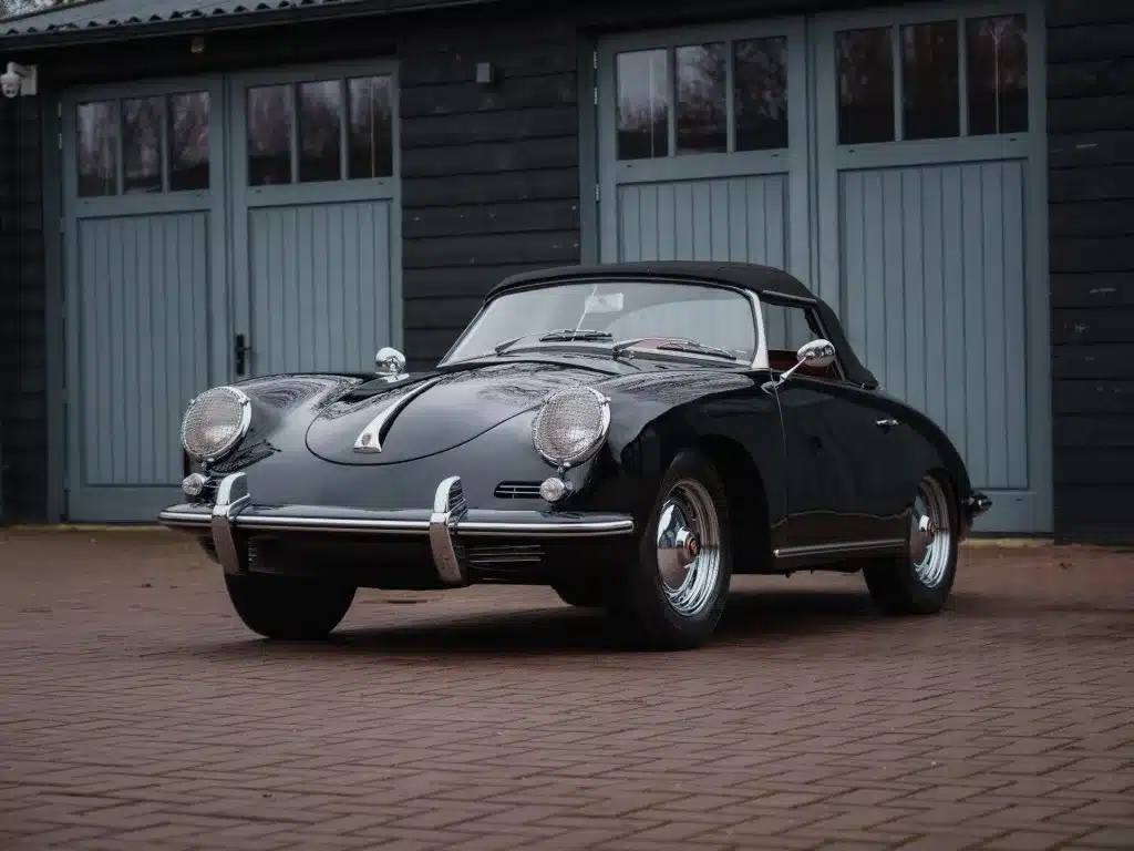 Porsche 356 B Roadster von 1960, schwarze Karosserie, Cabriolet, vor grauer Garage stehend.