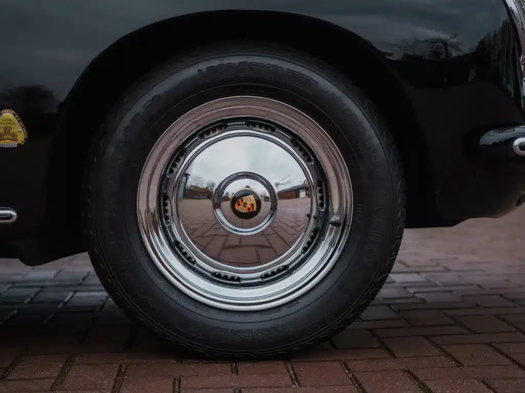 Verchromte Felge mit Porsche-Wappen eines Porsche 356 B Roadster von 1960 in Nahaufnahme.