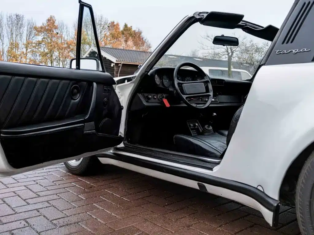 Innenansicht eines weißen Porsche 911 3.2 Targa mit offener Fahrertür und Blick ins Cockpit