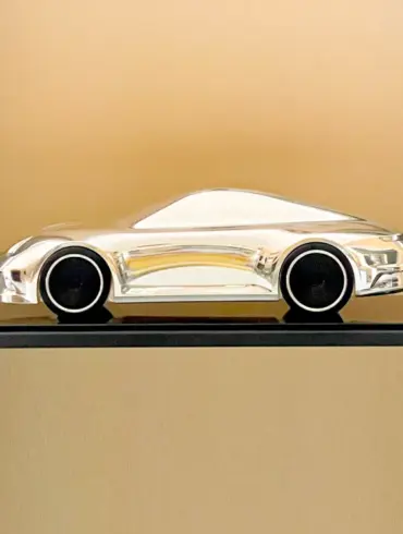 Aluminium-Skulptur eines Porsche 992 auf schwarzem Sockel mit hochglanzpolierter Oberfläche und schwarzen Felgen.