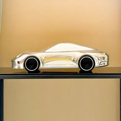 Aluminium-Skulptur eines Porsche 992 auf schwarzem Sockel mit hochglanzpolierter Oberfläche und schwarzen Felgen.