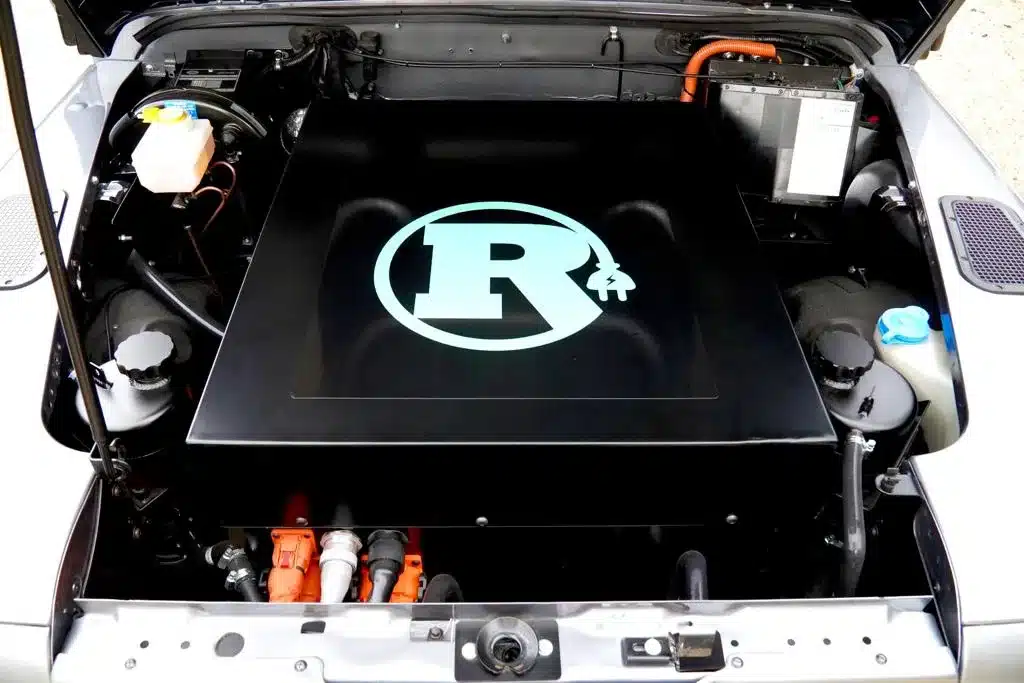 Motorraum eines Land Rover Defender mit eingebautem Rivolve EV-Elektroantrieb, deutlich erkennbares R-Logo auf der Abdeckung
