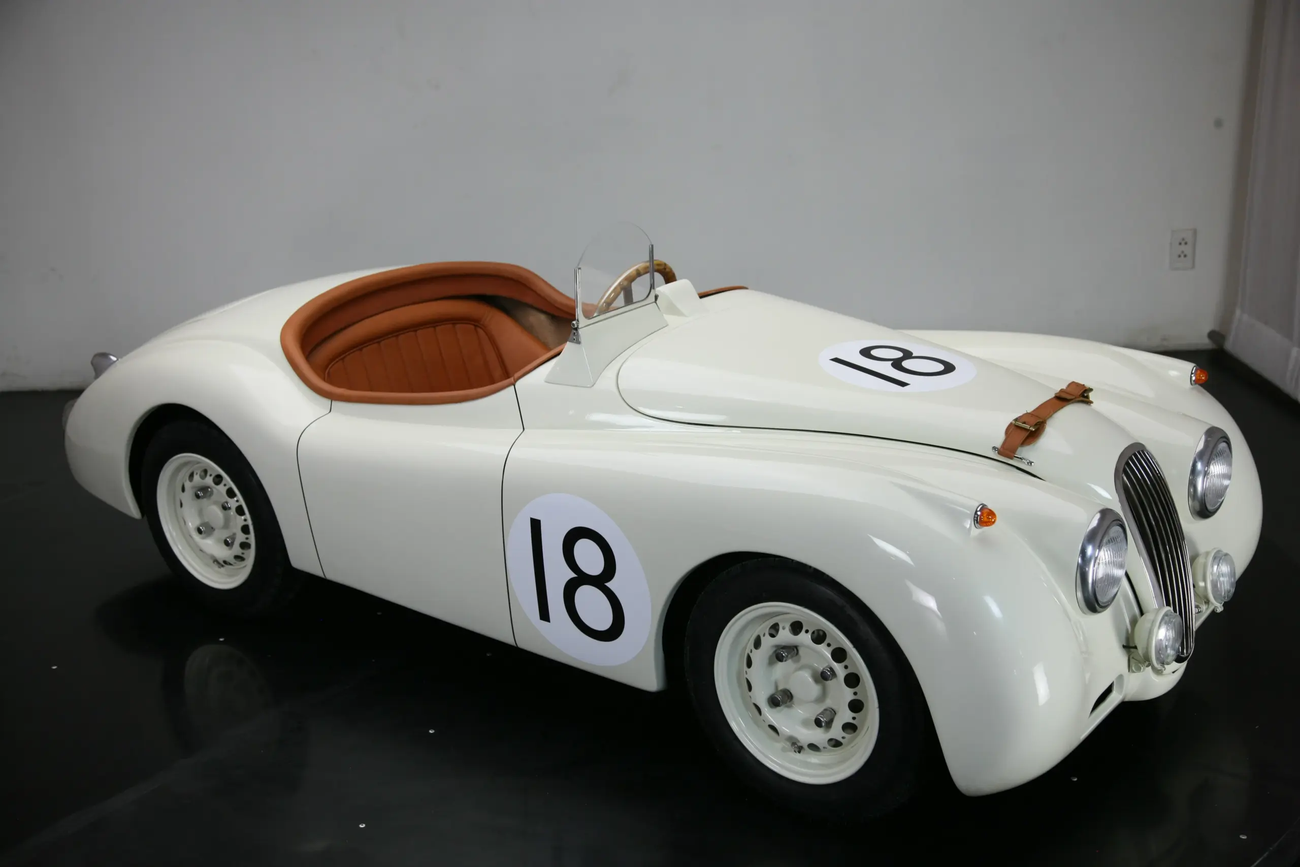 Weiße Miniatur-Replik des Jaguar XK120 Roadster mit Nummer 18, Ledersitzen und klassischen Designelementen.