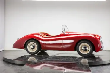 Seitliche Ansicht eines XK120 Roadster Red als verkleinerte Replik, handgefertigt mit roter Karosserie, Aluminiumelementen und klassischen Details.