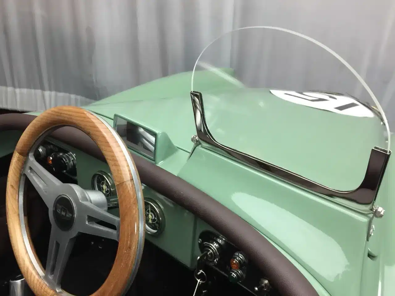 Blick auf das Holzlenkrad, Armaturenbrett und Windschutzscheibe eines verkleinerten XK120 Roadster Red