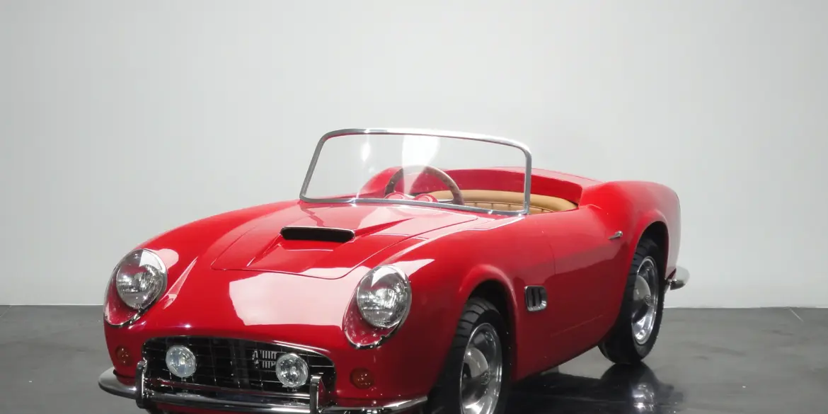 Rotes Spyder Junior Car im Stil eines klassischen Sportwagens, halbgroßes Kinderfahrzeug auf schwarzem Studiohintergrund.