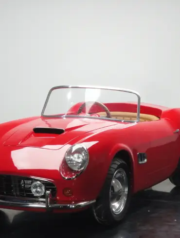 Rotes Spyder Junior Car im Stil eines klassischen Sportwagens, halbgroßes Kinderfahrzeug auf schwarzem Studiohintergrund.