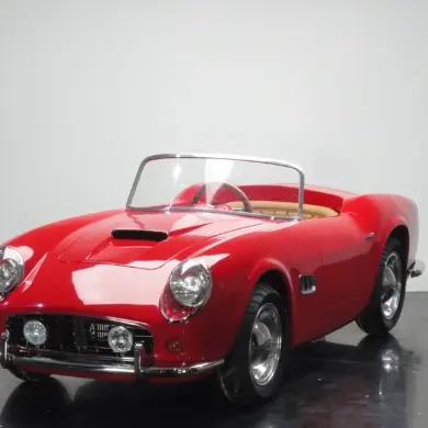 Rotes Spyder Junior Car im Stil eines klassischen Sportwagens, halbgroßes Kinderfahrzeug auf schwarzem Studiohintergrund.