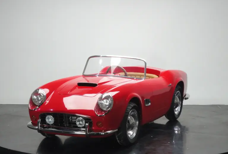 Rotes Spyder Junior Car im Stil eines klassischen Sportwagens, halbgroßes Kinderfahrzeug auf schwarzem Studiohintergrund.