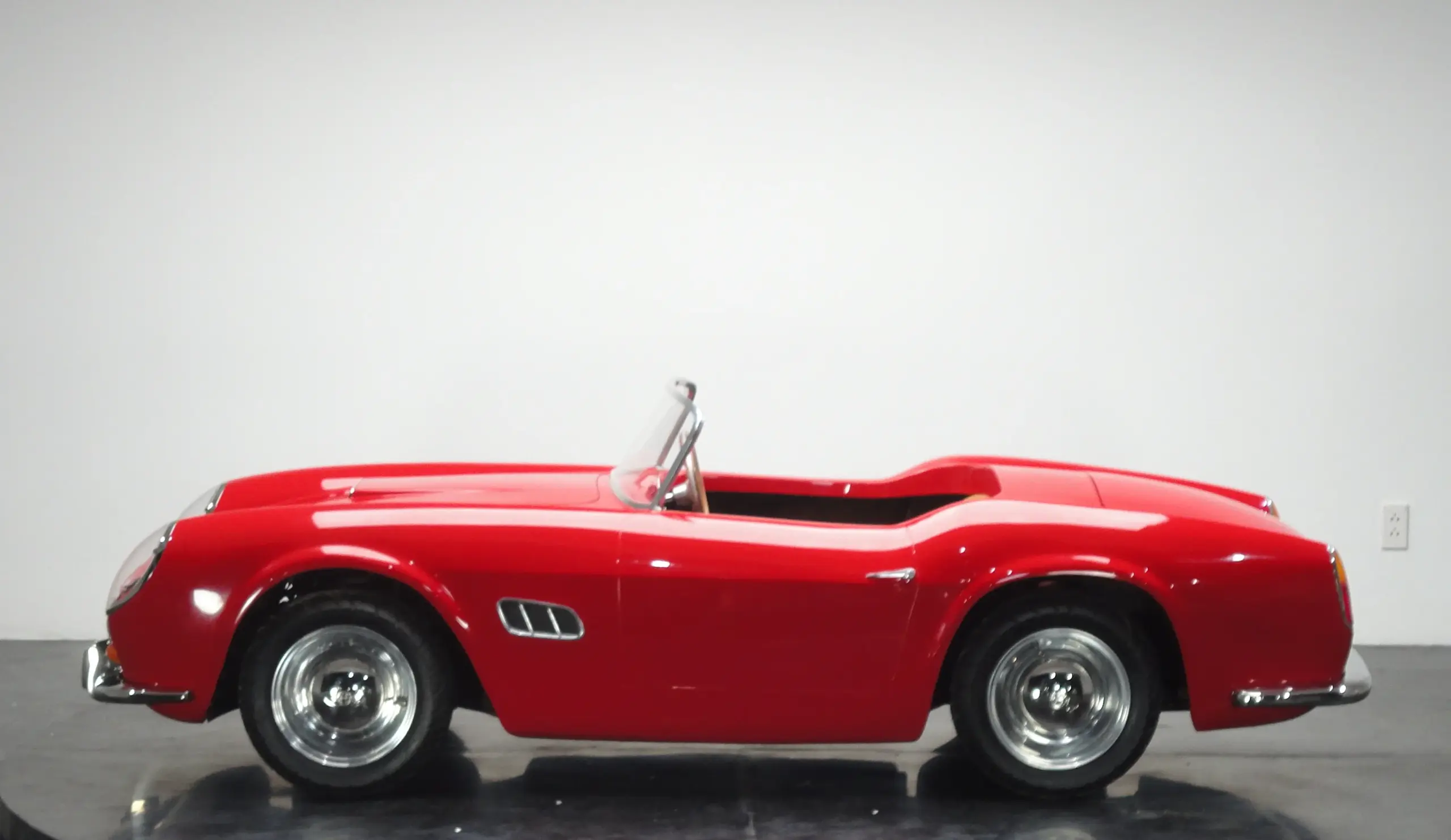 Rotes Spyder Junior Car im Stil eines klassischen Sportwagens, seitlich fotografiert